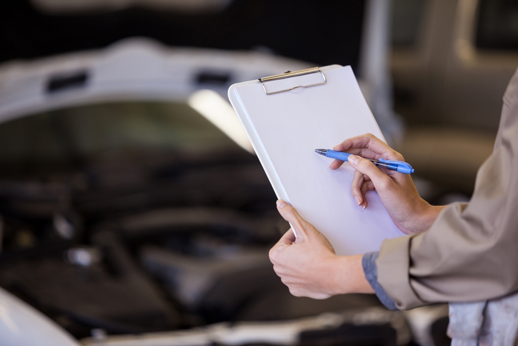 A car mechanic assessing a car in a workshop