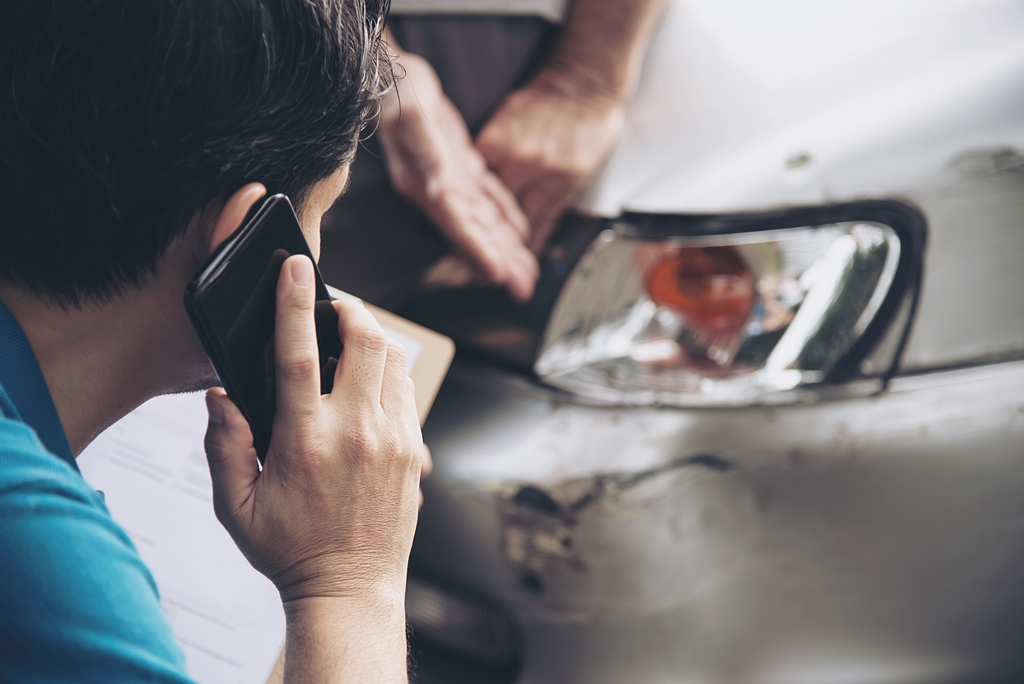 A man calling his insurance company claiming his car is damaged due to a road accident