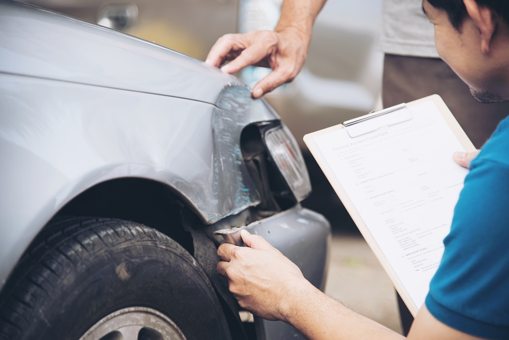 An insurance adjuster assessing the damages to a car
