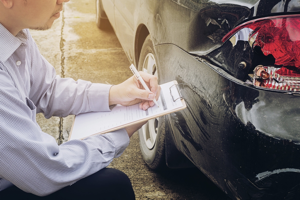 An insurance adjuster estimating the cost to repair the damaged parts of a car