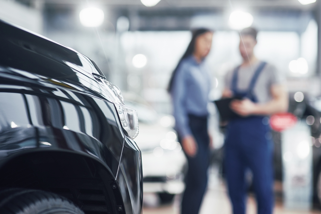 Female customer talking with a workshop mechanic about her car in the workshop