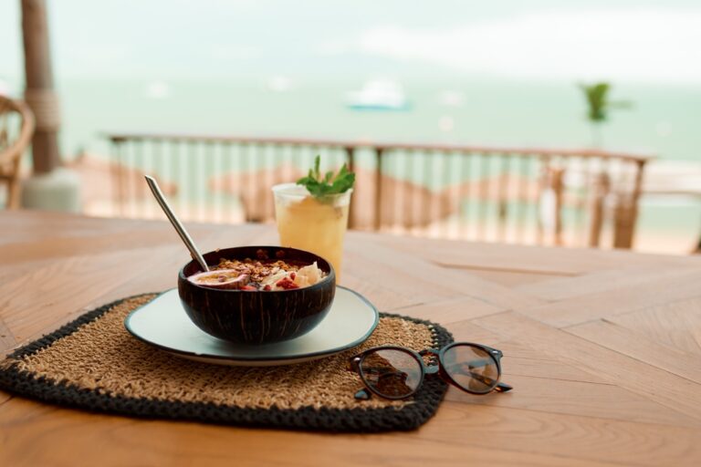 A bowl of smoothie on a table by the beach