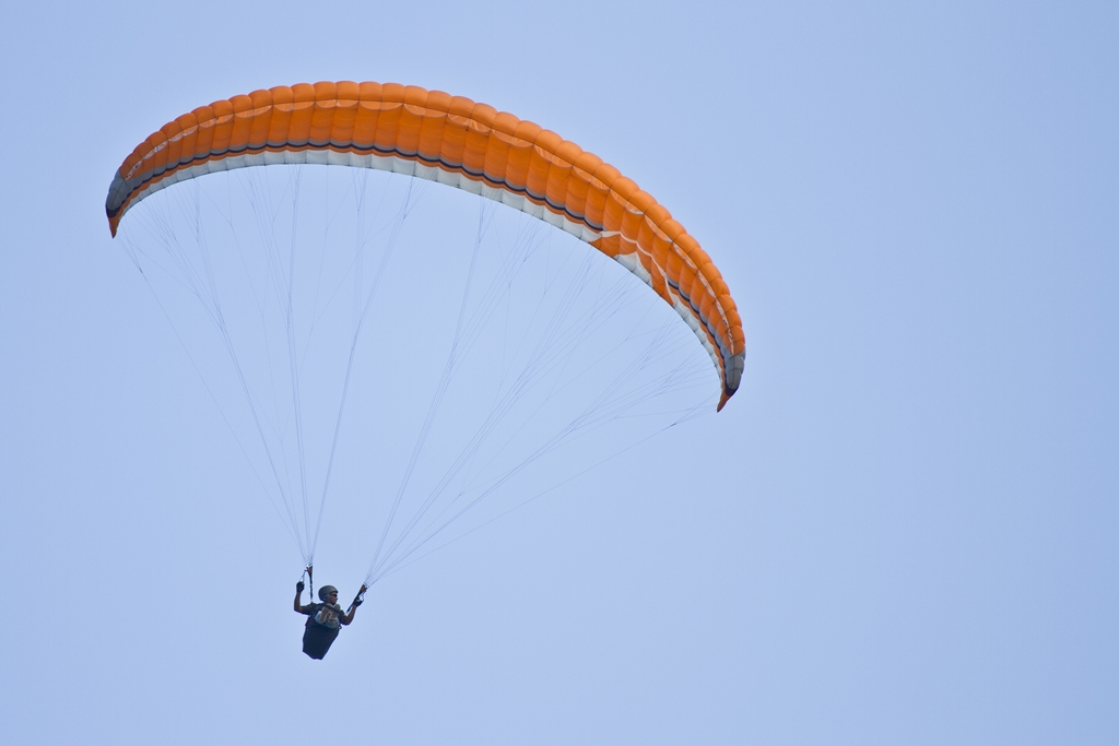 Amazing shot of a human paragliding in the blue sky