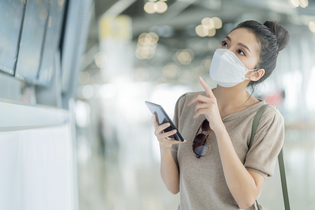 Asian female traveller checking her flight schedule at an airport