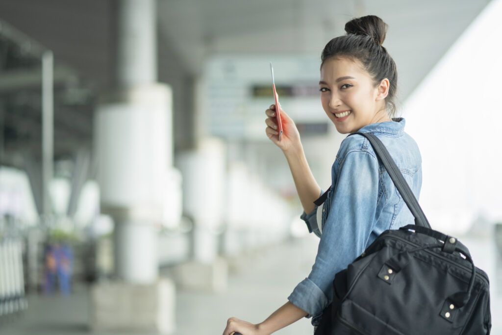 Asian female woman holding her passport and carrying her backpack and luggage