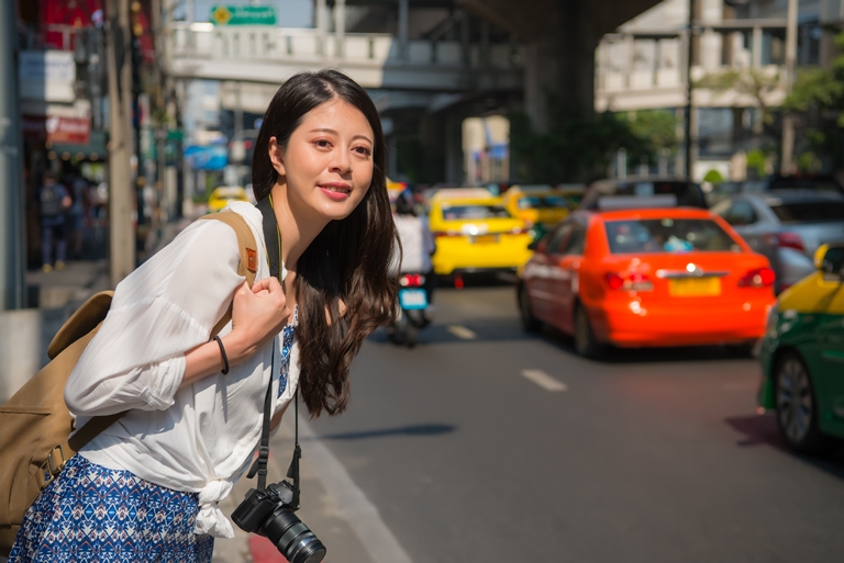 Asian female traveller by a busy road