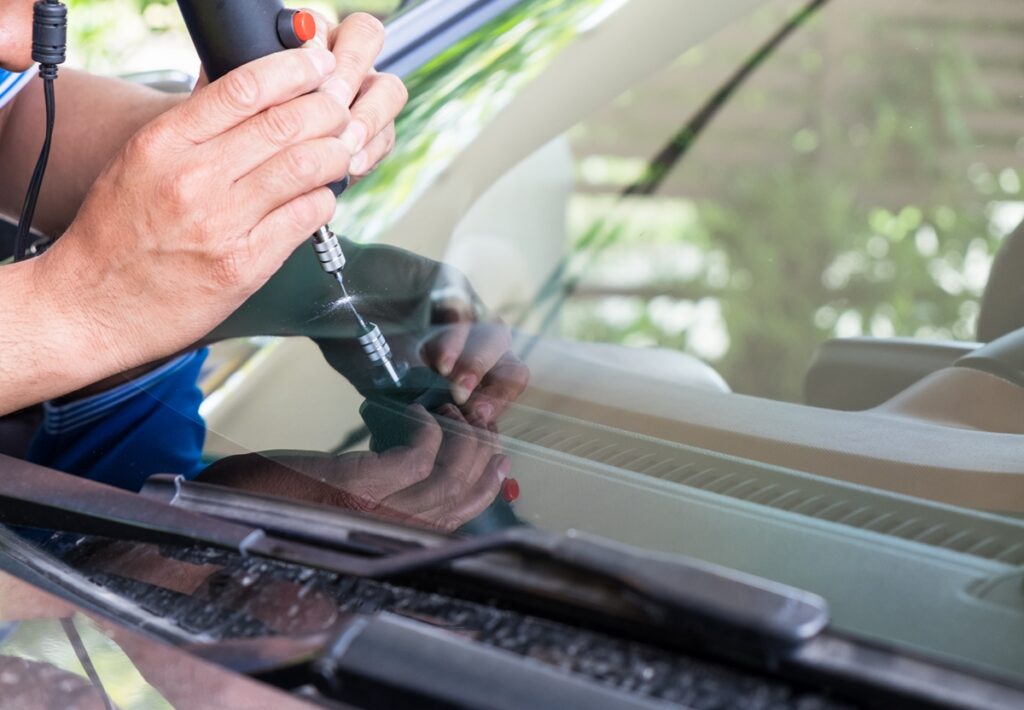 Glazier using tools repairing to fix a cracked windshield